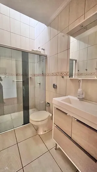 Banheiro com box de vidro e bancada clara.