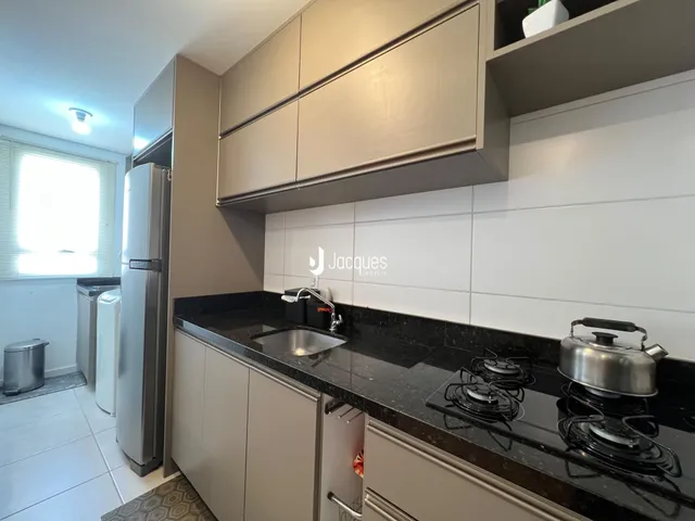 Cozinha moderna com armários e bancadas escuras em um imóvel no Brasil.