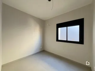 Ambiente interno com paredes brancas e uma grande janela.