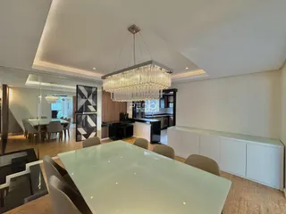 Sala de jantar ampla com lustre de cristal em um ambiente moderno.