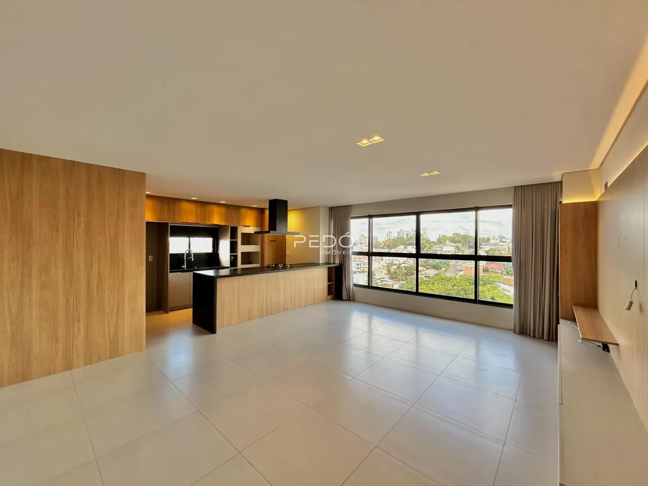 Sala de estar com cozinha moderna e grandes janelas.