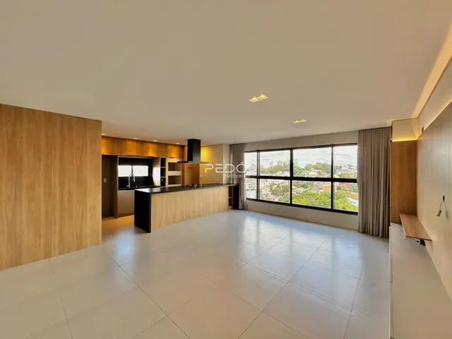 Sala de estar com cozinha moderna e grandes janelas.