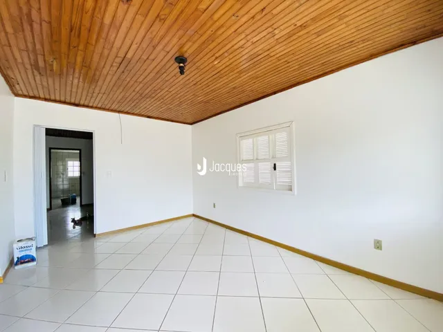 Uma sala ampla com piso de cerâmica branca e teto de madeira.