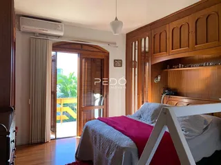 Quarto com armários de madeira e porta de vidro que dá acesso ao exterior.