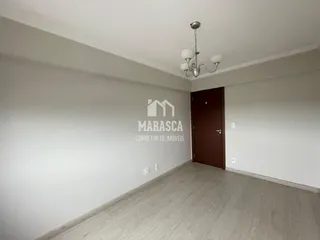 Interior de uma sala com piso de madeira e paredes brancas.