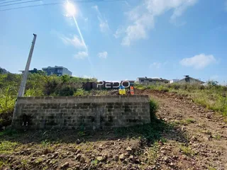 Parede de pedra rústica em um terreno árido sob um céu azul.
