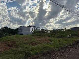 Foto de um terreno com vegetação e um prédio ao fundo em Lajeado.