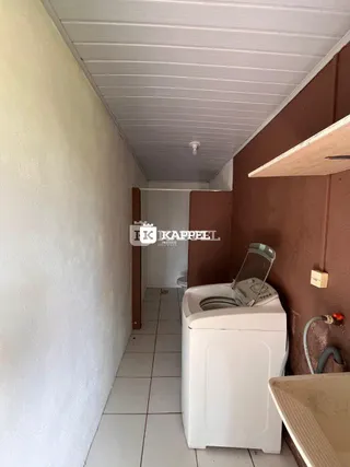 Corredor interno com paredes brancas e piso de azulejos claros.