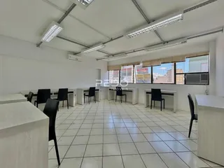 Ambiente interno de um escritório amplo com piso de cerâmica branca.