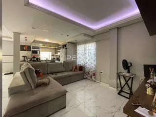 Sala de estar com sofá e cozinha em um apartamento no Brasil.