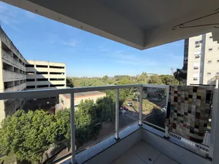Vista panorâmica da varanda mostrando a paisagem urbana e a vegetação circundante.