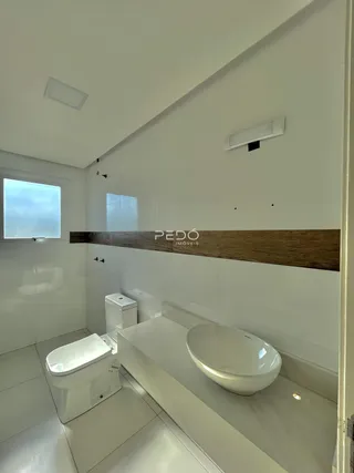 Banheiro moderno com revestimento branco e detalhes em madeira.
