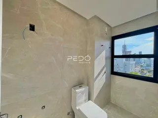 Foto de um banheiro com paredes em mármore claro e janela com vista da cidade.
