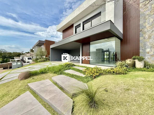 Fachada moderna de uma residência com paisagismo verde e área externa.