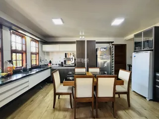Foto de uma cozinha e sala de jantar com piso de madeira e armários brancos.