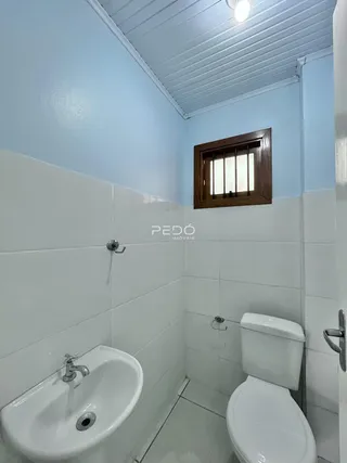 Foto de um banheiro com azulejos brancos e louças sanitárias.