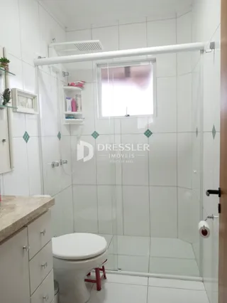 Um banheiro com revestimento cerâmico e box de vidro.