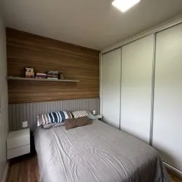 Quarto com cama e cabeceira de madeira.