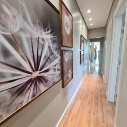 Foto de um corredor interno com piso de madeira e parede branca.