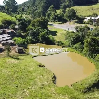 Uma paisagem de colinas verdes com um corpo d'água em uma propriedade.