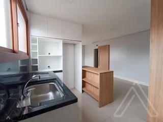 Cozinha moderna com bancada escura e armários brancos.