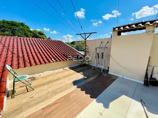 Vista externa de uma casa com telhado de telhas vermelhas e área de lazer ao ar livre.