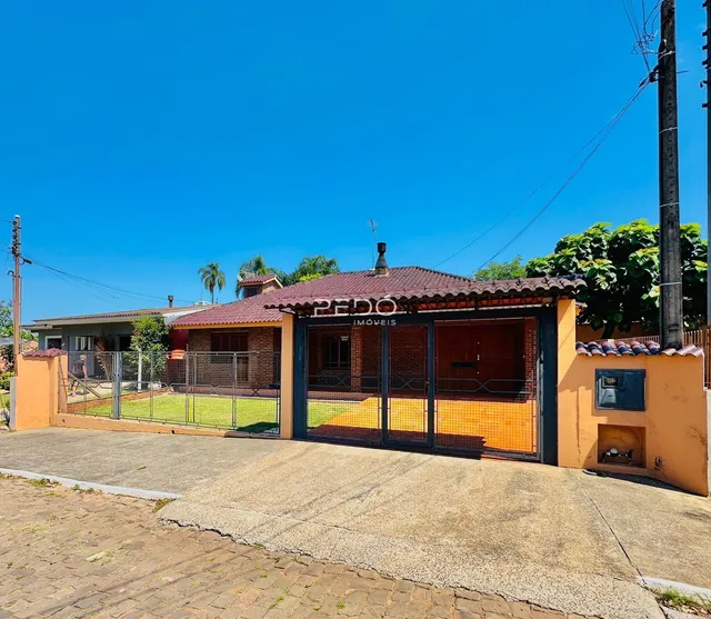 Fachada de uma residência em Lajeado, Brasil, com telhado de telhas e portão de metal.