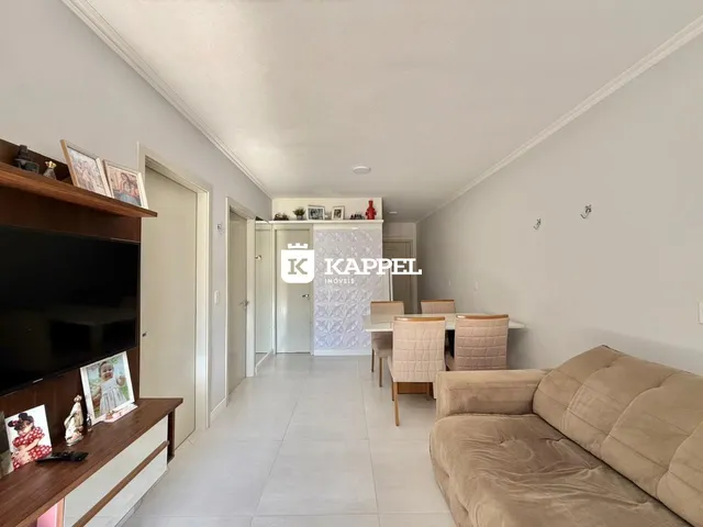 Uma sala de estar clara com sofá e mesa de jantar em um ambiente bem iluminado.
