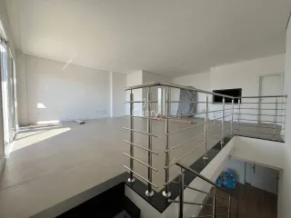 Vista de um ambiente interno com escadaria e grandes janelas.
