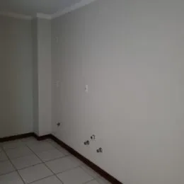 Foto de um corredor interno com piso de cerâmica branca.