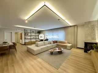 Sala de estar com sofá grande, mesa de centro e piso de madeira clara.