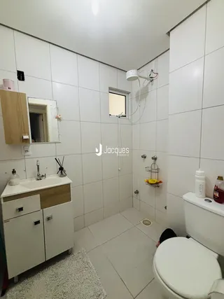 Foto de um banheiro com revestimento cerâmico branco e bancada de madeira.