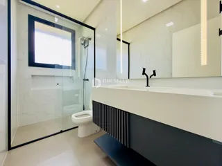 Banheiro moderno com revestimento em mármore e box de vidro.