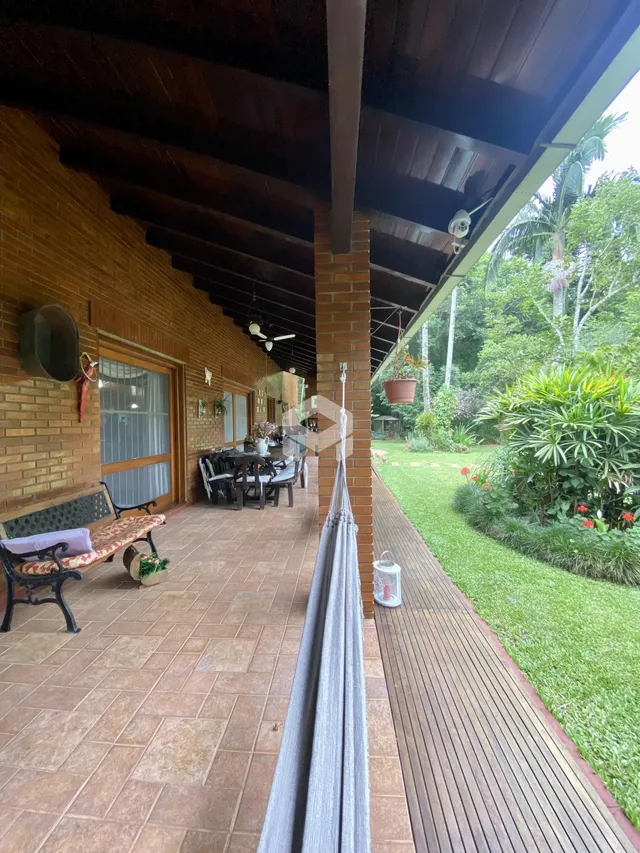 Vista da área externa com piso de tijolo e deck ao lado de um jardim.