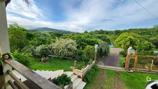 Vista externa de uma propriedade com jardim e vegetação exuberante.