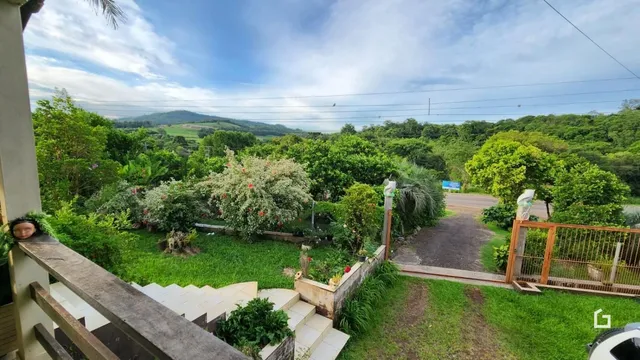 Vista externa de uma propriedade com jardim e vegetação exuberante.