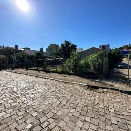 Vista externa de uma área pavimentada com paralelepípedos sob céu azul.