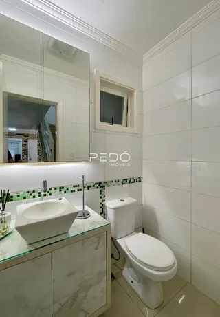 Foto de um banheiro com revestimento branco e louças sanitárias.