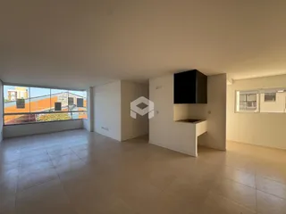 Sala ampla com piso de cerâmica e grandes janelas voltadas para o exterior.