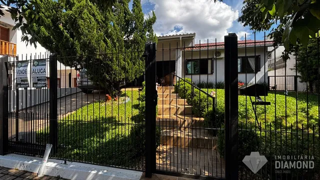 Fachada de uma residência com portão de ferro e jardim.