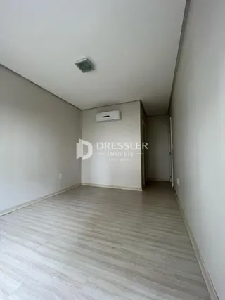 Foto de um ambiente interno com piso de madeira clara e paredes brancas.