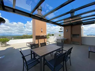 Vista de uma área externa com mesa de jantar e estrutura de telhado de vidro.