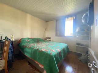 Quarto com cama e piso de madeira no interior da propriedade.