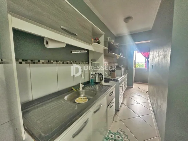 Vista da cozinha com armários brancos e bancada cinza.