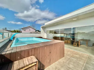 Piscina externa com deck de madeira em uma propriedade.