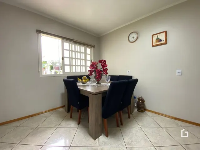 Foto de uma sala de jantar com mesa de madeira e janelas.