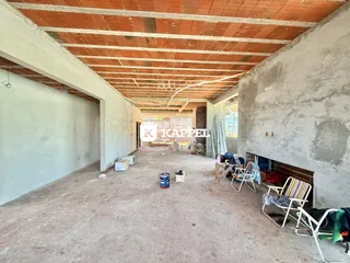 Vista interna de um espaço amplo em construção com teto de telha de barro exposto.