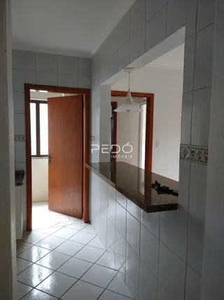 Hall com paredes de azulejo branco e porta de madeira.