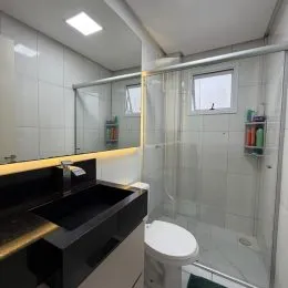 Foto de um banheiro com box de vidro e revestimento cerâmico.