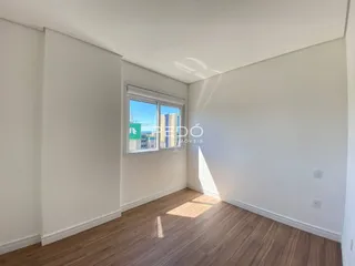 Ambiente interno de uma sala com piso de madeira clara e paredes brancas.